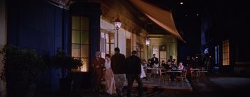 Movie still from “Lust for Life” (1956), directed by George Cukor – A group of people standing outside of a restaurant; Wide shot, High angle