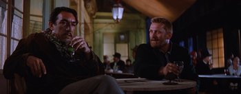 Movie still from “Lust for Life” (1956), directed by George Cukor – Two men sitting at a table in front of other people; Medium shot, Over the shoulder angle