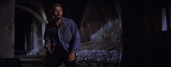 Movie still from “Lust for Life” (1956), directed by George Cukor – A man standing next to a wall in a dark room; Medium shot, Low angle