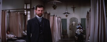 Movie still from “Lust for Life” (1956), directed by George Cukor – A man standing in front of a row of curtains in a room; Medium shot, Low angle