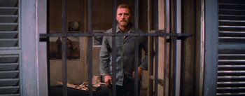 Movie still from “Lust for Life” (1956), directed by George Cukor – A man standing behind bars in a jail cell; Wide shot, Low angle