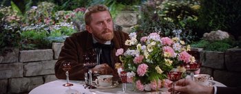 Movie still from “Lust for Life” (1956), directed by George Cukor – A man sitting at a table with a glass of red wine; Medium shot, Over the shoulder angle