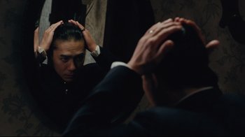 Movie still from “Lust, Caution” (2007), directed by Ang Lee – A man in a suit combing his hair in a mirror; Close Up shot, Over the shoulder angle