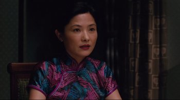 Movie still from “Lust, Caution” (2007), directed by Ang Lee – A woman in a colorful dress sitting in a dark room; Close Up shot, Over the shoulder angle