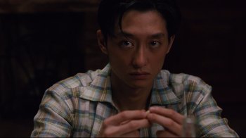 Movie still from “Lust, Caution” (2007), directed by Ang Lee – A young man in a plaid shirt is holding his hands up to his face; Close Up shot, Over the shoulder angle