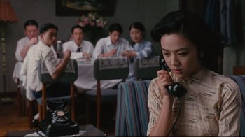 Movie still from “Lust, Caution” (2007), directed by Ang Lee – A group of people sitting at a table with a phone to their ear; Medium shot, High angle
