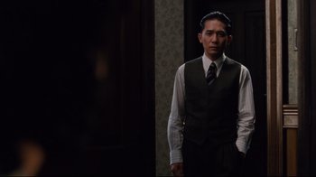 Movie still from “Lust, Caution” (2007), directed by Ang Lee – A man wearing a suit and tie standing in a room; Medium shot, Low angle