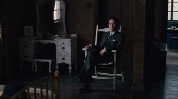 Movie still from “Lust, Caution” (2007), directed by Ang Lee – A man sitting in a rocking chair in a room; Wide shot, High angle