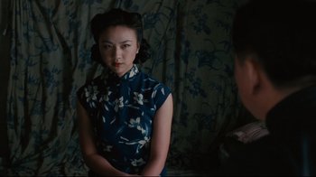Movie still from “Lust, Caution” (2007), directed by Ang Lee – A woman in a blue dress is sitting in front of a curtain; Medium shot, Over the shoulder angle