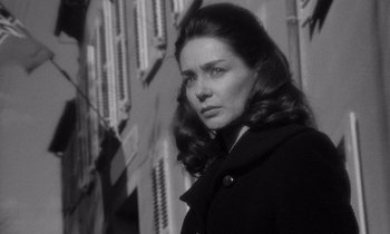 Movie still from “Léon Morin, Priest” (1961), directed by Jean-Pierre Melville – Black and white photograph of a woman in front of a building; Close Up shot, Low angle