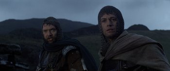 Movie still from “Macbeth” (1971), directed by Roman Polanski – Two men dressed in medieval clothing standing next to each other in a field; Medium shot, Low angle