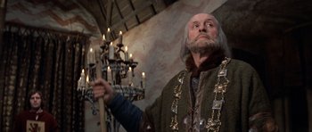 Movie still from “Macbeth” (1971), directed by Roman Polanski – An old man holding a stick in front of a chandelier; Medium shot, Low angle