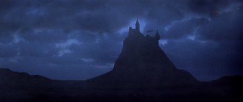 Movie still from “Macbeth” (1971), directed by Roman Polanski – A castle on top of a hill under a cloudy sky at night; Extreme Wide shot, Low angle