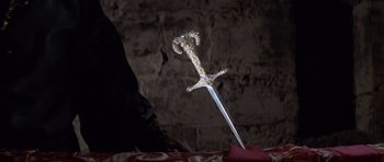 Movie still from “Macbeth” (1971), directed by Roman Polanski – A metal sword is on a table in front of a brick wall; Close Up shot, High angle