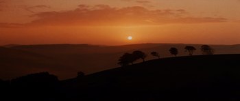 Movie still from “Macbeth” (1971), directed by Roman Polanski – The sun is setting on a hill with trees on it; Extreme Wide shot, Low angle