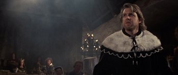 Movie still from “Macbeth” (1971), directed by Roman Polanski – A group of people gathered in a room with lights in the background; Medium shot, Low angle