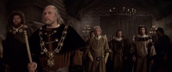 Movie still from “Macbeth” (1971), directed by Roman Polanski – A group of men in medieval garb standing in a room; Medium shot, Low angle