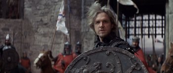 Movie still from “Macbeth” (1971), directed by Roman Polanski – A man in a black jacket holding a metal shield; Close Up shot, Over the shoulder angle