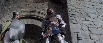 Movie still from “Macbeth” (1971), directed by Roman Polanski – A man dressed as a medieval knight standing in front of a stone wall; Medium shot, Low angle