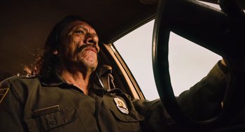 Movie still from “Machete” (2010), directed by Robert Rodriguez – A man driving a car in the middle of the day; Close Up shot, Low angle