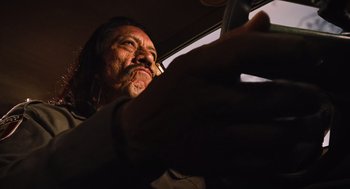 Movie still from “Machete” (2010), directed by Robert Rodriguez – A man with long hair and a mustache looking at a cell phone; Close Up shot, Low angle