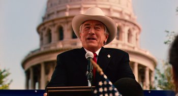 Movie still from “Machete” (2010), directed by Robert Rodriguez – A man wearing a white cowboy hat is speaking at a podium; Medium shot, Over the shoulder angle