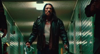 Movie still from “Machete” (2010), directed by Robert Rodriguez – A man with long black hair and a leather jacket holding a bag; Medium shot, Low angle