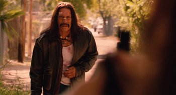 Movie still from “Machete” (2010), directed by Robert Rodriguez – A man with long hair is walking down the street; Medium shot, Over the shoulder angle