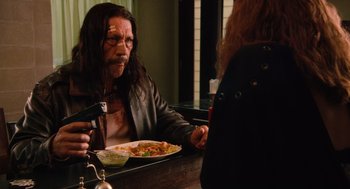 Movie still from “Machete” (2010), directed by Robert Rodriguez – A man sitting at a table with a plate of food in front of him; Medium shot, Over the shoulder angle