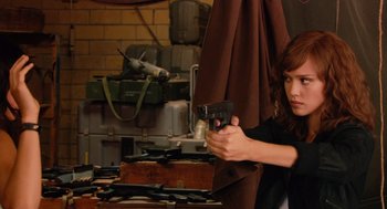 Movie still from “Machete” (2010), directed by Robert Rodriguez – A woman holding a gun in a room with luggage; Medium shot, Over the shoulder angle