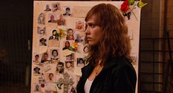 Movie still from “Machete” (2010), directed by Robert Rodriguez – A woman standing in front of a wall covered in pictures; Close Up shot, Over the shoulder angle