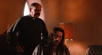 Movie still from “Machete” (2010), directed by Robert Rodriguez – A priest standing next to a man with long hair; Medium shot, Low angle
