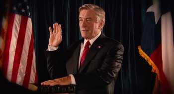 Movie still from “Machete” (2010), directed by Robert Rodriguez – An older man in a suit and red tie is holding his hand up; Medium shot, Low angle