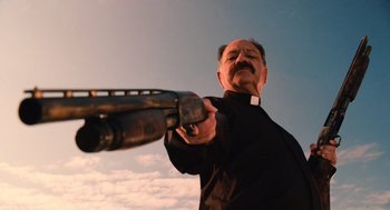 Movie still from “Machete” (2010), directed by Robert Rodriguez – A man in a priest's outfit holding a gun; Medium shot, Low angle