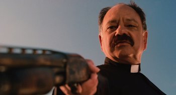 Movie still from “Machete” (2010), directed by Robert Rodriguez – A man in a priest's outfit is holding a gun; Close Up shot, Low angle