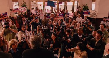 Movie still from “Machete” (2010), directed by Robert Rodriguez – A group of people gathered in a room holding microphones; Extreme Wide shot, High angle