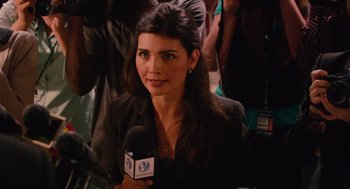 Movie still from “Machete” (2010), directed by Robert Rodriguez – A woman is holding a microphone while sitting in front of a crowd; Close Up shot, High angle