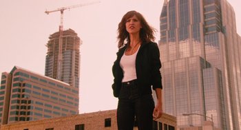 Movie still from “Machete” (2010), directed by Robert Rodriguez – A woman standing in front of a building with a crane in the background; Medium shot, Low angle