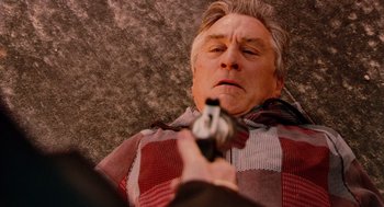 Movie still from “Machete” (2010), directed by Robert Rodriguez – An older man laying on the ground holding a gun; Close Up shot, Overhead angle