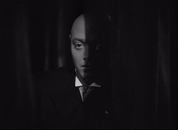 Movie still from “Mad Love” (1935), directed by Karl Freund – A man in a suit and tie in the dark; Close Up shot, Low angle