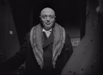 Movie still from “Mad Love” (1935), directed by Karl Freund – A man with a bald head wearing a fur collar; Medium shot, Low angle