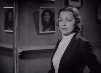 Movie still from “Mad Love” (1935), directed by Karl Freund – A black and white photo of a woman in a suit; Medium shot, Over the shoulder angle