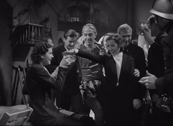 Movie still from “Mad Love” (1935), directed by Karl Freund – A group of people standing around each other in a room; Medium shot, High angle