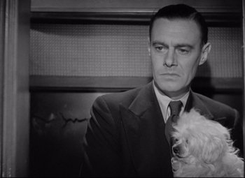 Movie still from “Mad Love” (1935), directed by Karl Freund – A black and white photo of a man holding a dog; Close Up shot, Low angle