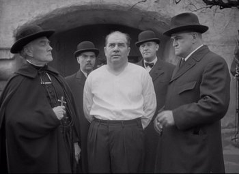 Movie still from “Mad Love” (1935), directed by Karl Freund – A group of men standing next to each other in front of a building; Medium shot, Low angle