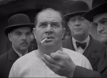 Movie still from “Mad Love” (1935), directed by Karl Freund – A black - and - white photo of a man smoking a cigarette; Medium shot, Low angle
