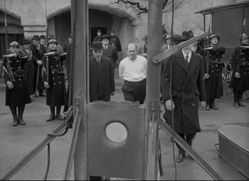 Movie still from “Mad Love” (1935), directed by Karl Freund – A group of men standing next to a guillotine; Wide shot, Low angle