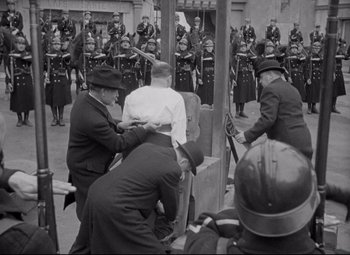 Movie still from “Mad Love” (1935), directed by Karl Freund – A group of men standing next to each other on a street; Wide shot, Low angle