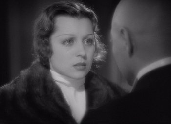 Movie still from “Mad Love” (1935), directed by Karl Freund – An old photo of a woman looking at a bald man; Close Up shot, Over the shoulder angle