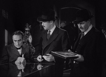 Movie still from “Mad Love” (1935), directed by Karl Freund – A group of men standing next to each other in a room; Medium shot, High angle